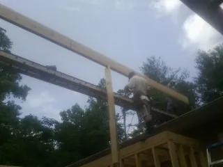 Carpenter setting a ridge beam over a new addition frame — Ice Dam Removal by Roofing Brothers in Palco