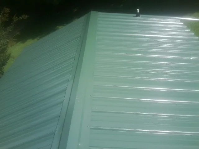 New green metal panels meeting at the ridge of a roof — Flat Roof Repair work by our crew in Palco