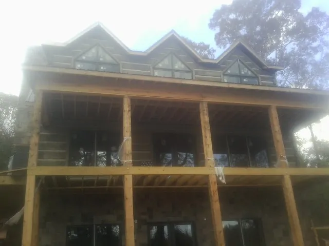 Dormers and porch framing on a large log home under construction — Roof Coating work by our crew in Palco