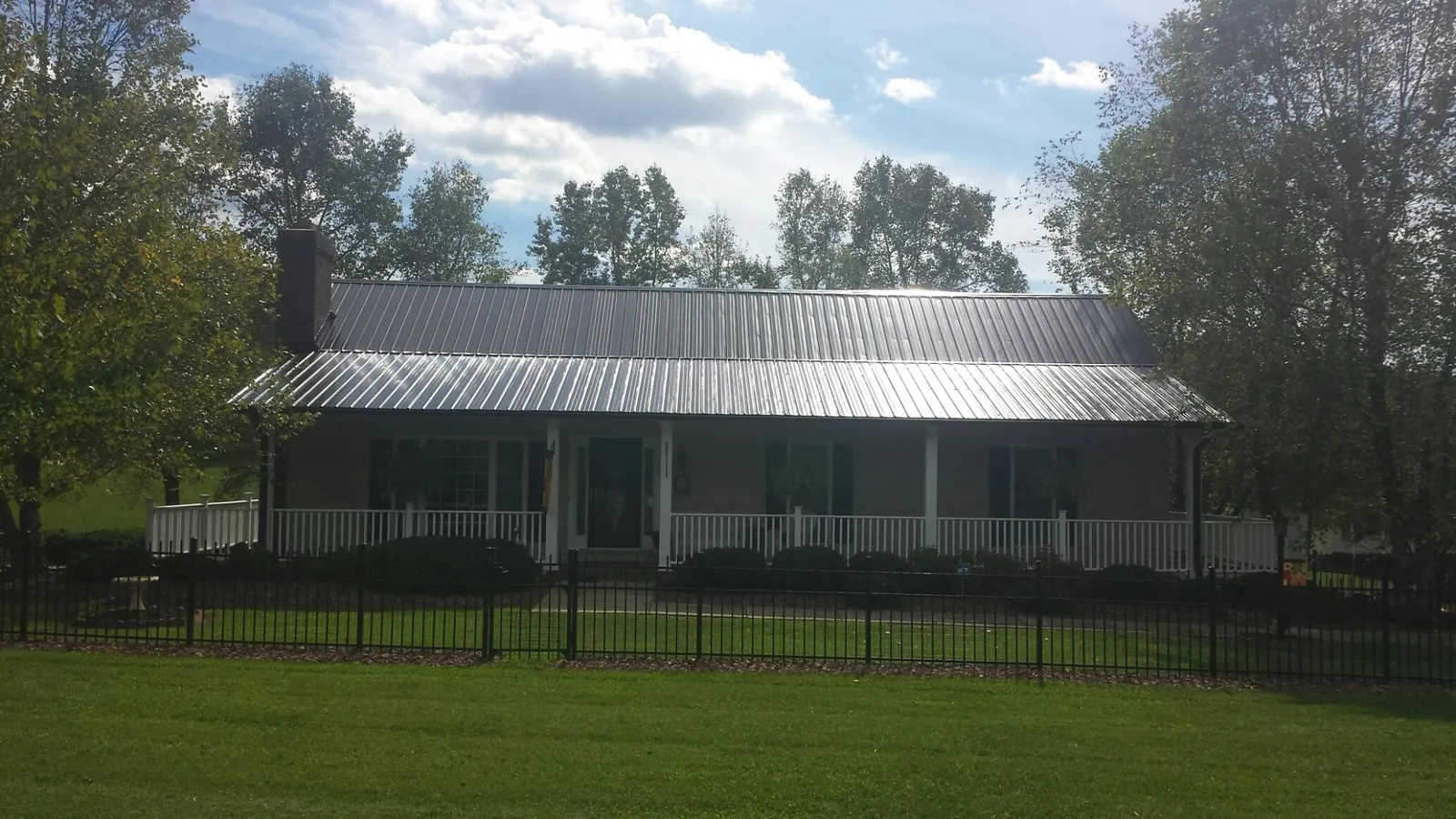 Gray metal roof on a brick ranch with a full width front porch — Gutter Guard Installation work by our crew in Palco