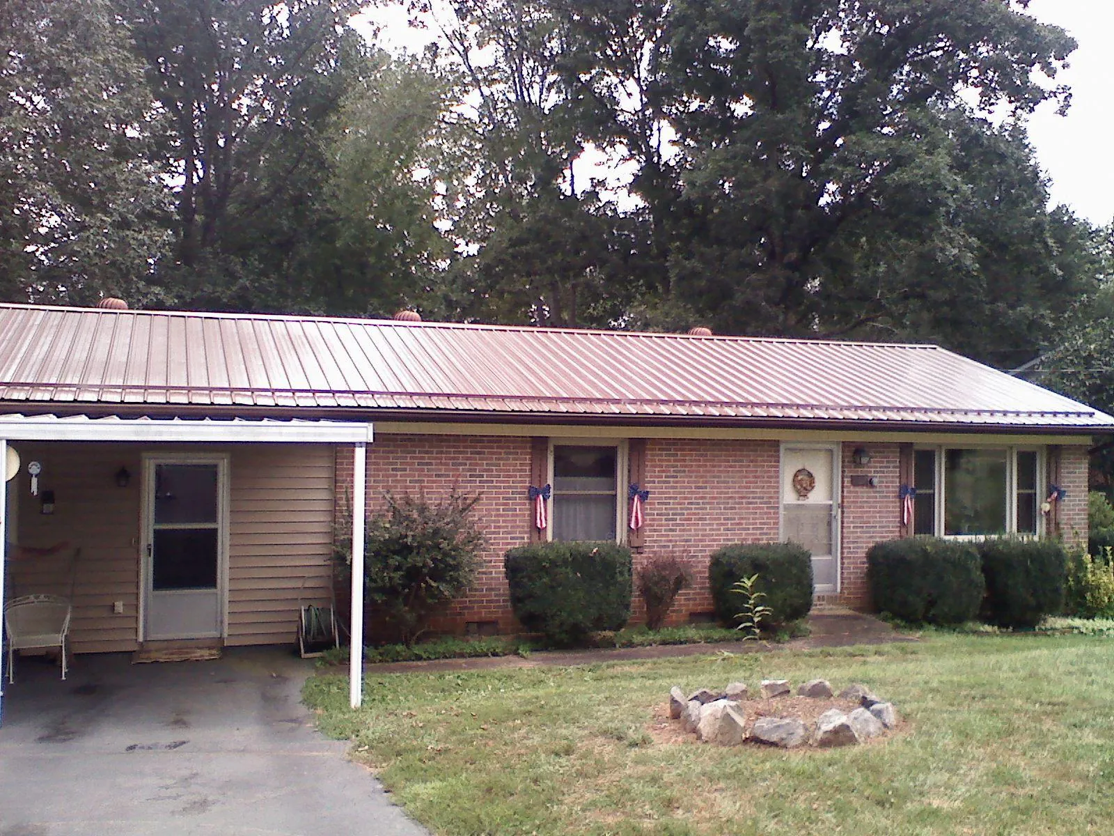 Bronze metal roof and carport on a brick ranch home — Roof Repair work by our crew in Palco