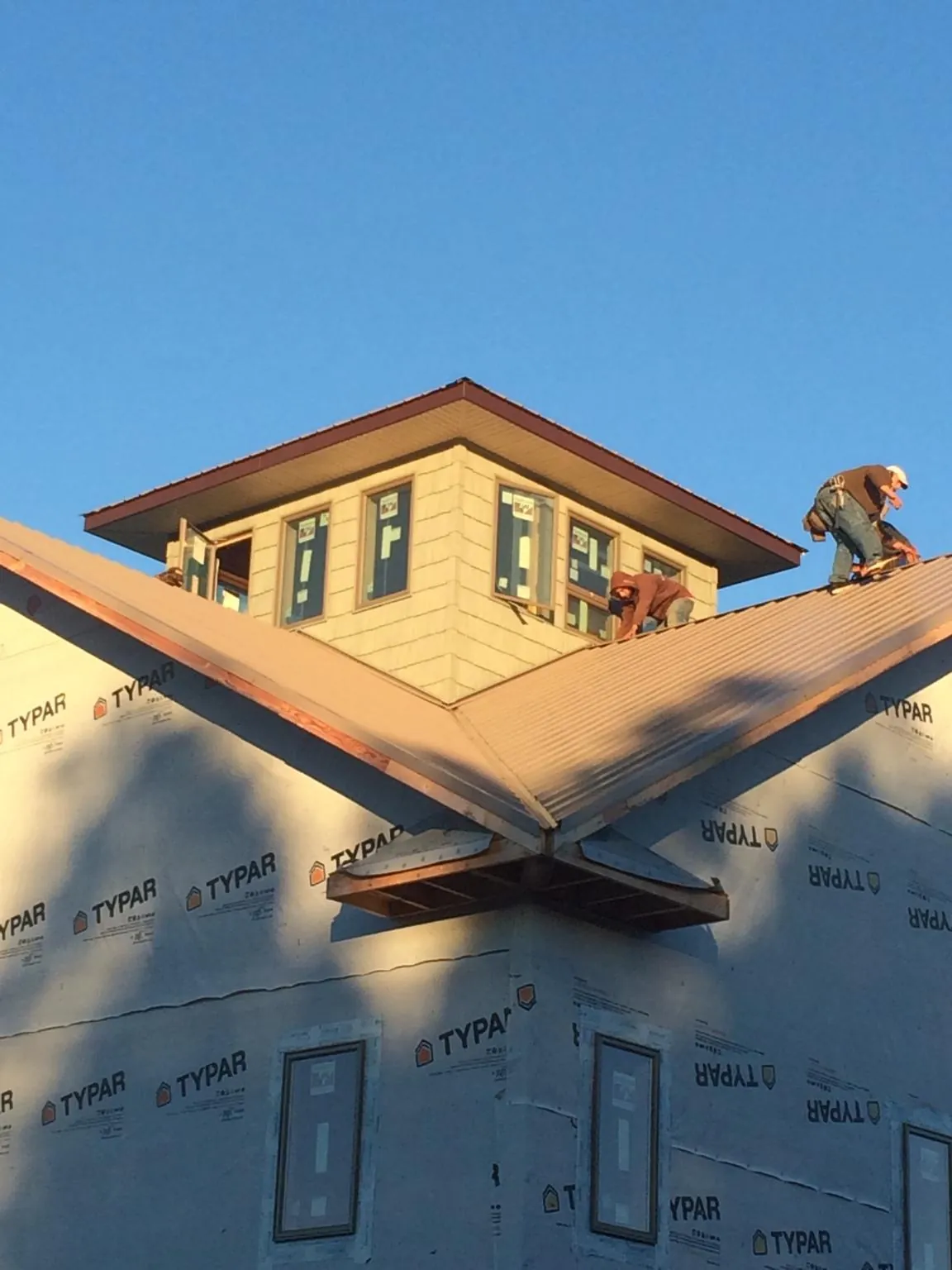 Roofers working around a rooftop cupola on a new metal roof at sunset — Roof Waterproofing in Palco by Roofing Brothers